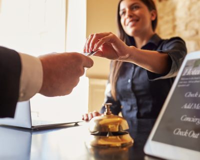 Guest takes room key card at check-in desk of hotel, close up
